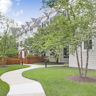 A well-maintained pathway meanders through a residential area lined with trees and greenery.