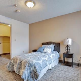 A cozy bedroom with a single bed and a nightstand, featuring neutral tones and simple decor.