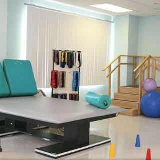 A physical therapy room equipped with exercise mats, therapy balls, and stairs.