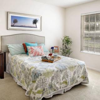 A cozy bedroom with colorful pillows, a decorative bedspread, and a window letting in natural light.