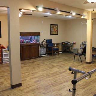 A rehabilitation room featuring exercise equipment, wooden flooring, and an aquarium.