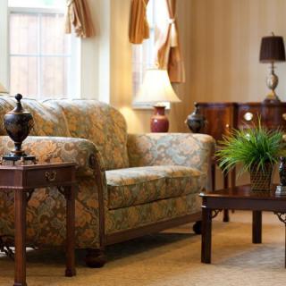 A cozy living room with a patterned sofa, wooden coffee and side tables, and decorative lamps.