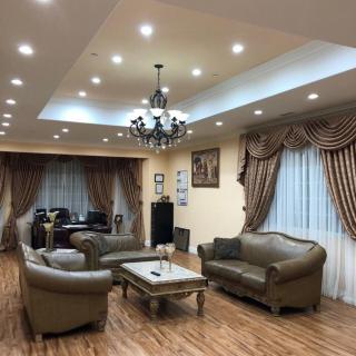 A spacious living room featuring elegant sofas, a coffee table, and a chandelier under recessed lighting.