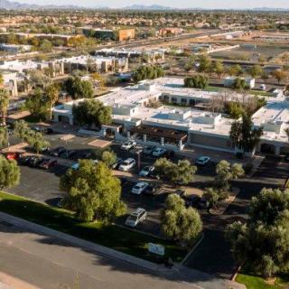Aerial view of a commercial area with buildings and parking lots surrounded by trees.