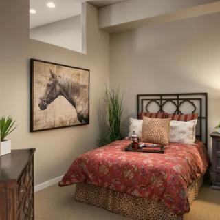 Cozy bedroom with warm decor featuring a horse painting and lush plants.