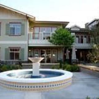 A two-story residential building with a central fountain in the courtyard.