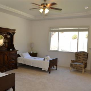 A spacious bedroom with two single beds, a wooden armoire, and a large window providing natural light.