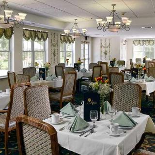 An elegant dining room with neatly arranged tables and chairs, adorned with chandeliers and table settings.