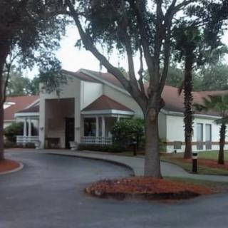 A residential building surrounded by trees with a circular driveway.