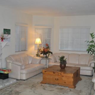 A cozy living room with white sofas, a wooden coffee table, and indoor plants.