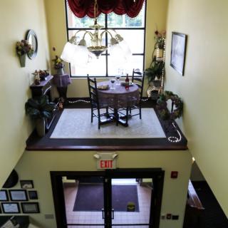 A cozy dining area above a hallway, featuring a small table set with chairs and decorative elements.