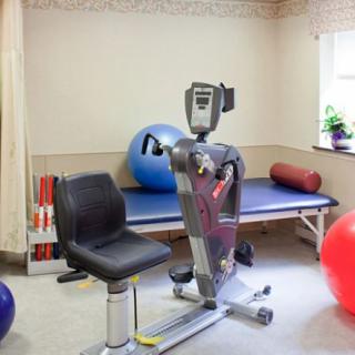 A rehabilitation room featuring exercise equipment including a stationary bike and therapy balls.