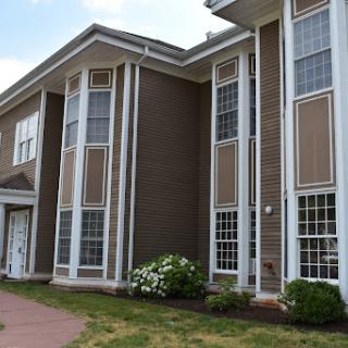 A modern residential building featuring large windows and a well-maintained lawn.