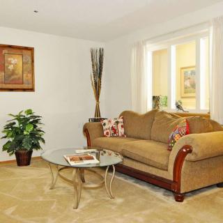 A cozy living room with a plush sofa, glass coffee table, and decorative plants.