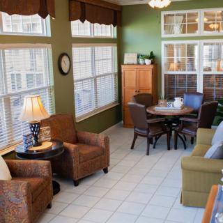 A cozy living room with abundant natural light, featuring comfortable seating and warm decor.