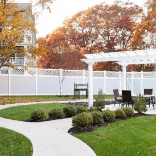 A beautifully landscaped garden featuring a pergola with outdoor seating, surrounded by autumn foliage.