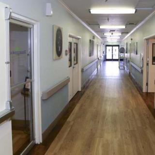 A quiet hospital corridor with doors on either side leading to patient rooms.