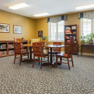 A cozy library reading room with tables, chairs, and bookshelves.