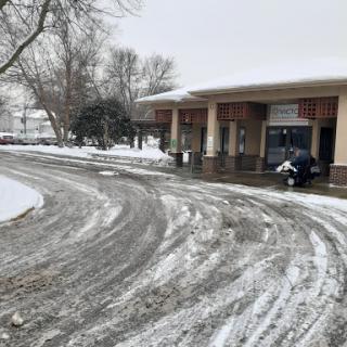 A snowy scene featuring a winding road near a building with a motorcycle parked.