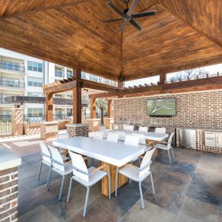 A modern outdoor patio with a dining area under a wooden pergola.