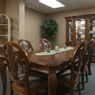 A cozy dining room featuring a wooden table surrounded by elegant chairs, complemented by a glass cabinet and indoor greenery.