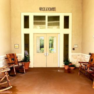 A welcoming entrance with rocking chairs and potted plants.