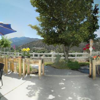 A scenic outdoor patio area with seating, umbrellas, and a view of the mountains in the background.
