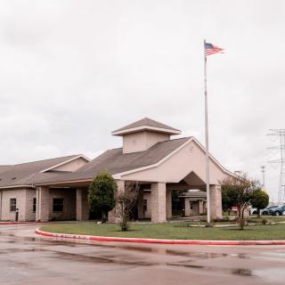A building with a flagpole displaying the American flag on a cloudy day.