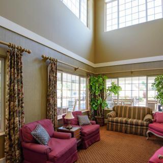A spacious living room with high ceilings, large windows, and comfortable seating.