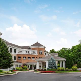 A picturesque residential building surrounded by lush greenery and a clear blue sky.