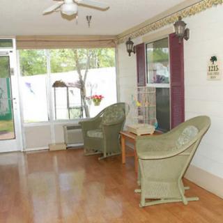 A cozy sunroom with wicker chairs, a small table, and large windows overlooking the garden.