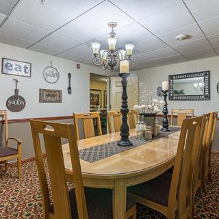 A cozy dining room featuring a large wooden table surrounded by chairs, adorned with a chandelier and decorative wall art.