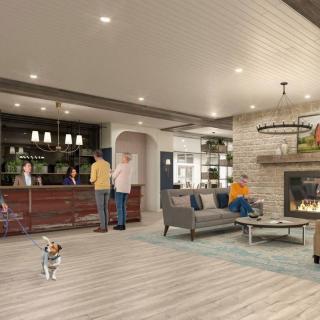 A modern lobby with a bar, fireplace, and seating area bustling with people and a dog.