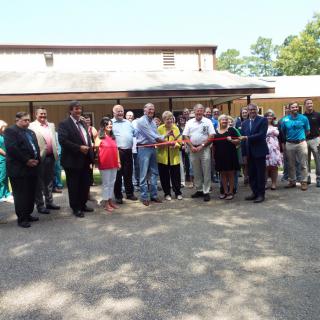 A group of people gathered outdoors for a ribbon-cutting ceremony.
