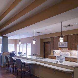 A modern kitchen with a long countertop and pendant lighting.