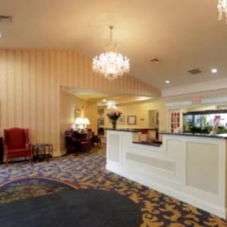 A hotel lobby with a reception desk, chandelier lighting, and elegant furnishings.