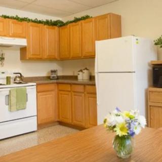 A cozy kitchen with wooden cabinets, a white refrigerator, and a vase of flowers on the table.