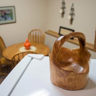 A wooden basket sits on a kitchen surface with a dining area in the background.