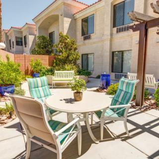 A sunny outdoor patio area with a table and chairs surrounded by greenery.