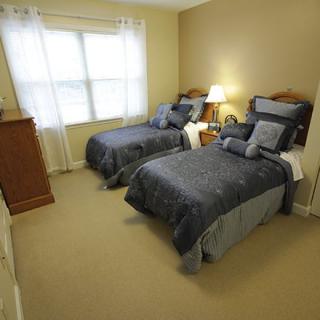 A cozy bedroom with twin beds and a lamp next to a window.
