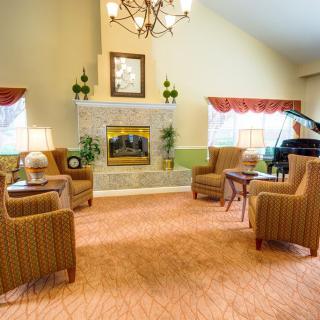 A cozy living room with a fireplace and comfortable seating, featuring elegant decor and a grand piano.