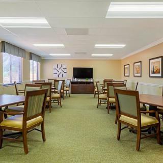 A spacious dining area with multiple tables and chairs, featuring a television and decorative wall art.