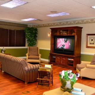 A cozy living room featuring a television, comfortable seating, and warm wooden flooring.