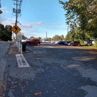 A view of a parking lot surrounded by trees and vehicles under a clear blue sky.