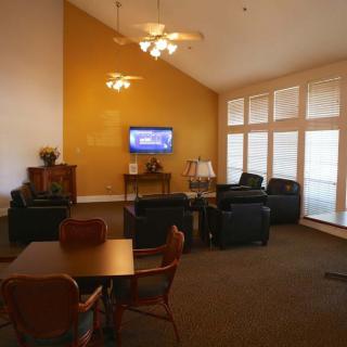 A cozy living room featuring comfortable seating, a television, and large windows.