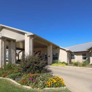 A modern residential building surrounded by landscaped gardens and a clear blue sky.