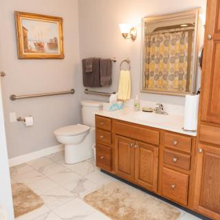 A well-lit bathroom with wooden cabinetry and tiled flooring.