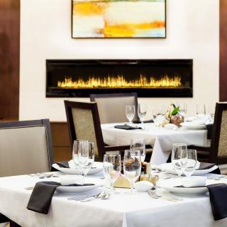 An elegantly set dining room with a modern fireplace in the background.