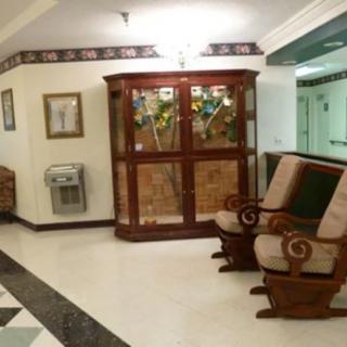 A cozy lobby area featuring cushioned chairs and a decorative cabinet along a corridor.
