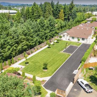 An aerial view of a residential property with a house, lawn, and surrounding greenery.